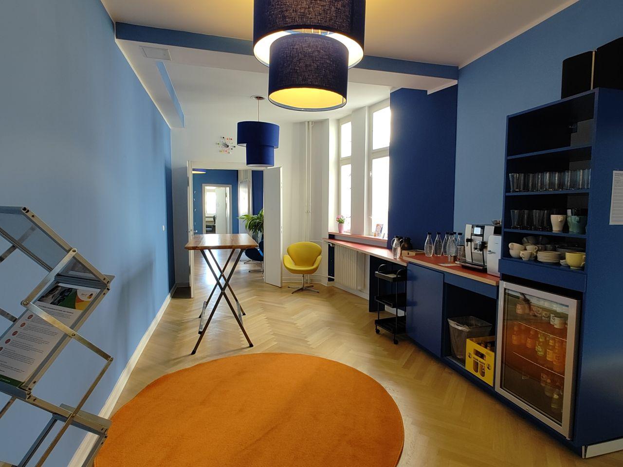 Lounge von meeet Wilmersdorf mit Blick auf die Kaffeetheke, einen Stehtisch und einen weiten Blick in den Flur