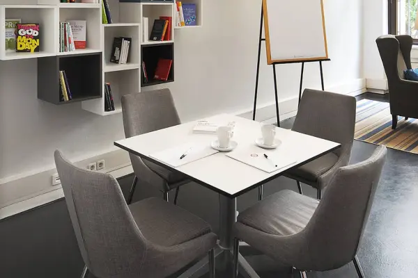 Meeet-Mitte-coachingraum-Study-600 Coachingraum mit quadratischem Besprechungstisch und einem Flipchartständer im Hintergrund